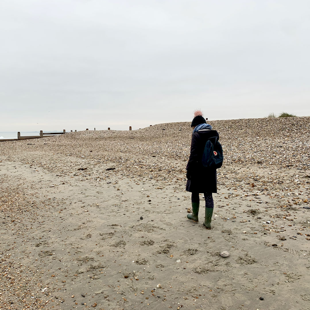 Sarah walking on a beach in the winter